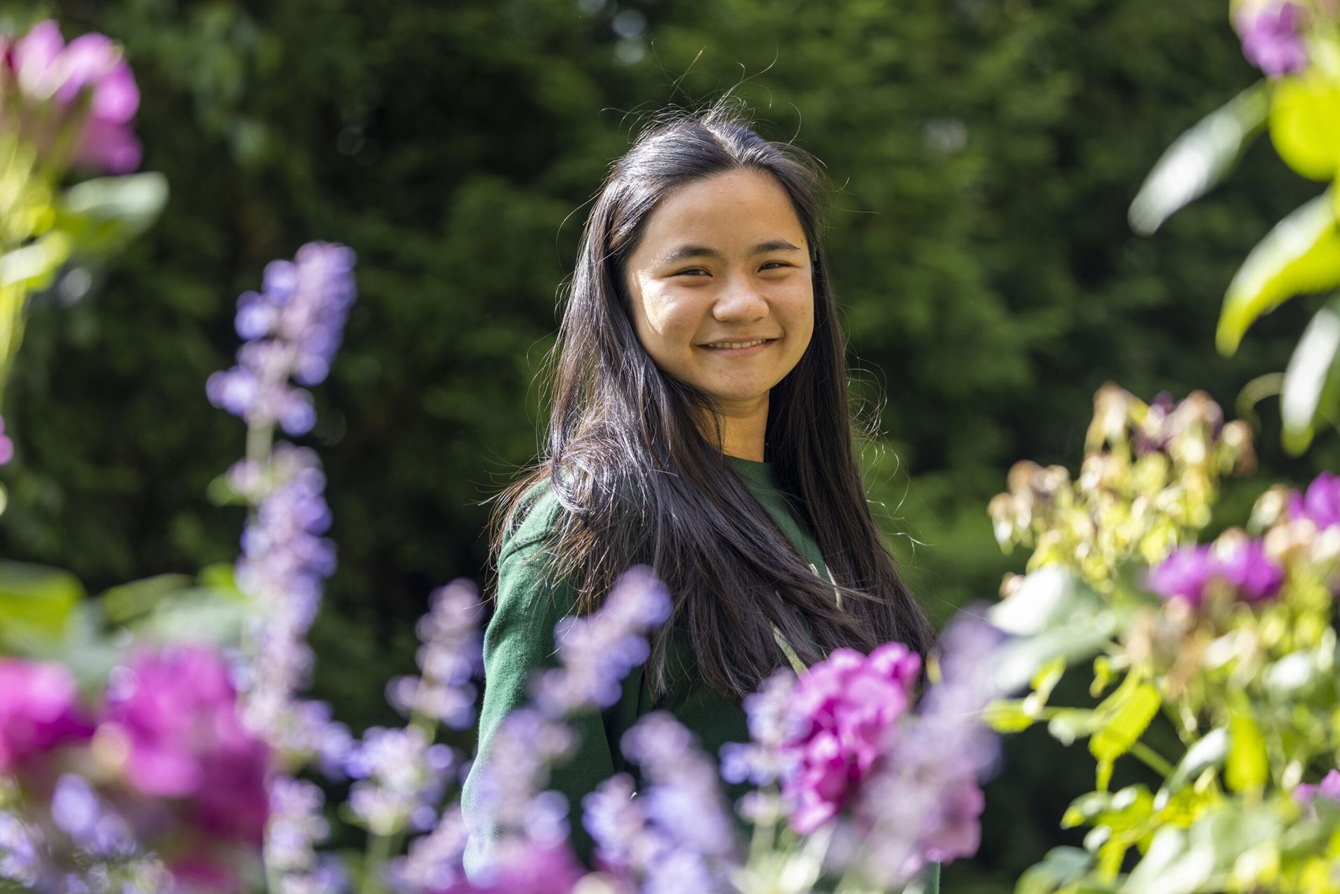 Student Eliza White in a garden surrounded by purple flowers.