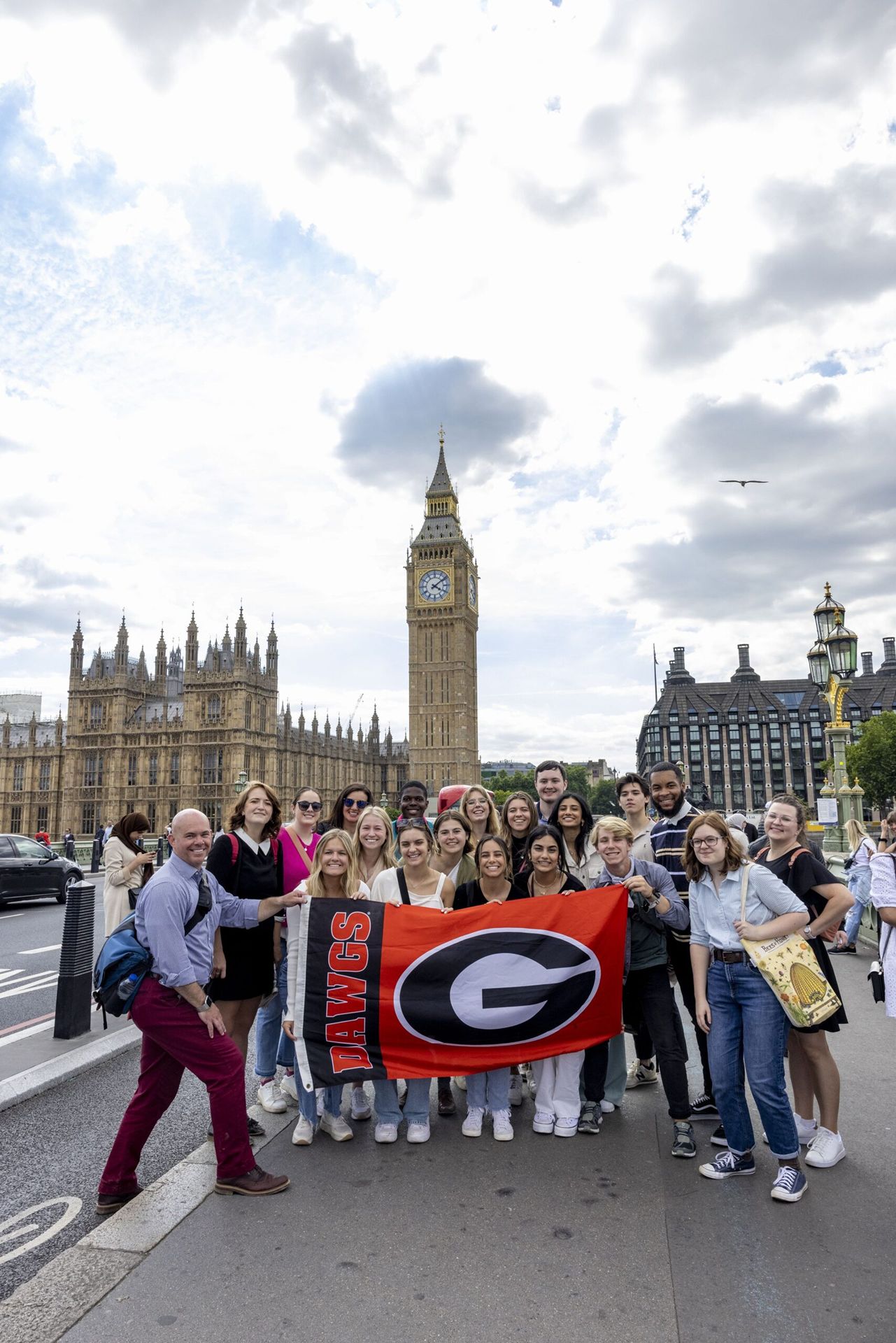 Roughly a dozen students pose for a photo with a University of Georgia flag in front of London’s Big Ben clock tower.