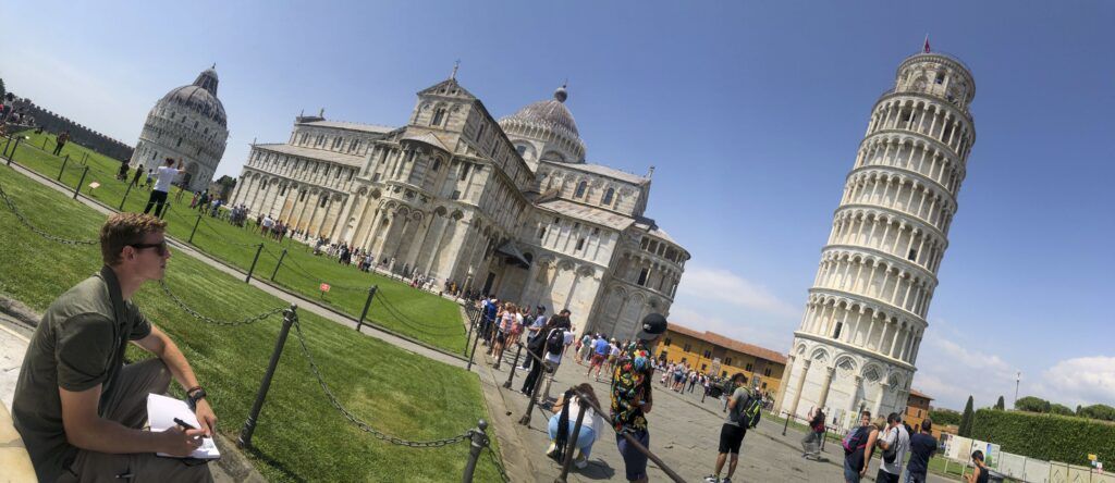 A wide shot of a large crowd of people in front of a classic European building. The photo is slightly tilted to the right.