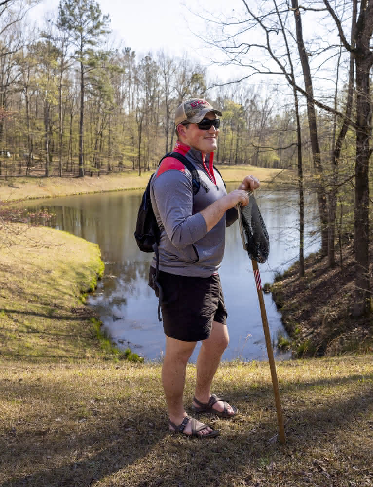 Séamus O’Brien outdoors in front of a pond where he conducts field research