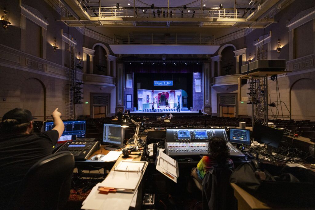 Two people from the UGA theatre department plan lighting design from the control room of a theatre.