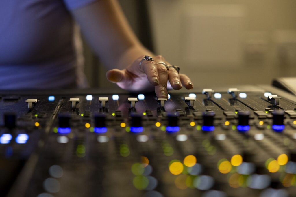 A closeup of a hand operating the sliding mechanics of a sound board.