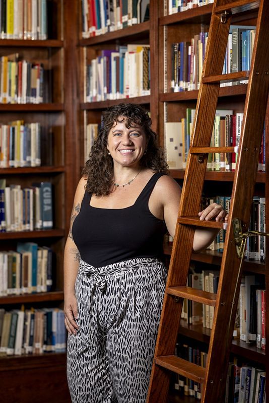 Julianne O'Connell standing and smiling in front of Fincher Library's bookshelves.