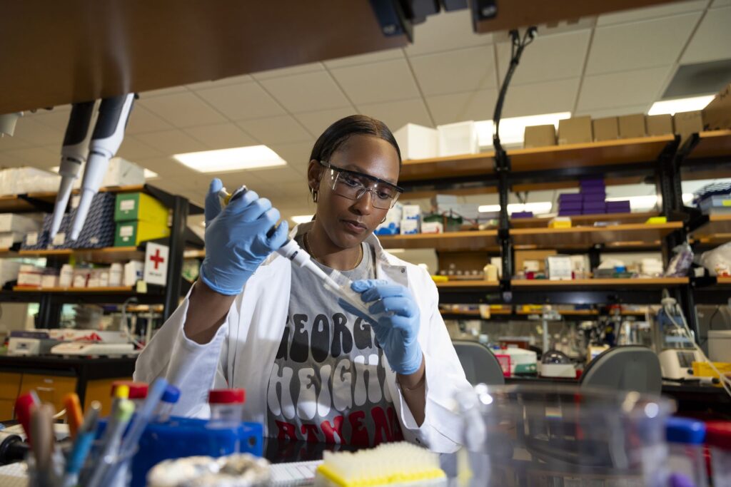 Autumn Hampton, a pre-med student at UGA, tests materials in a lab using small vials and injectors.