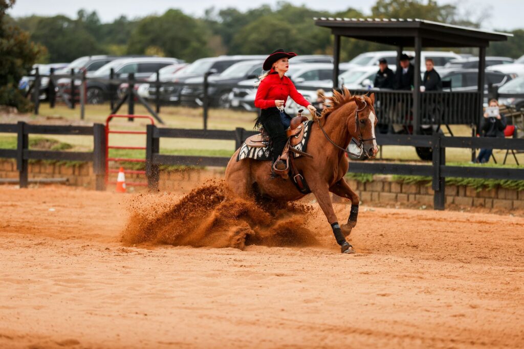 Caitlin Lyons, a student at UGA, competes in a horseback riding competition while wearing red and black equestrian gear.