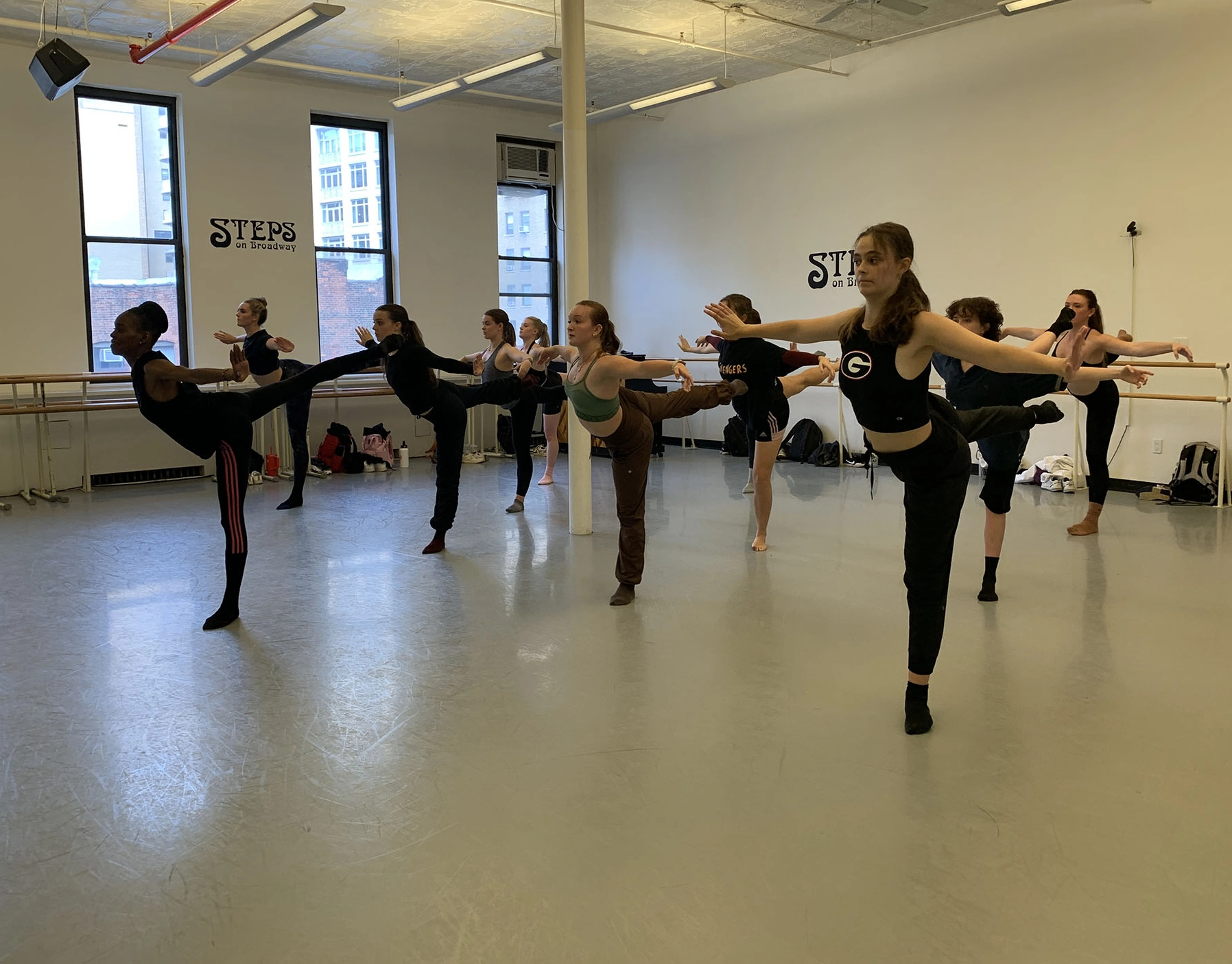 A group of dancers all post in an arabesque position during a dance class at STEPS on Broadway in New York City. 