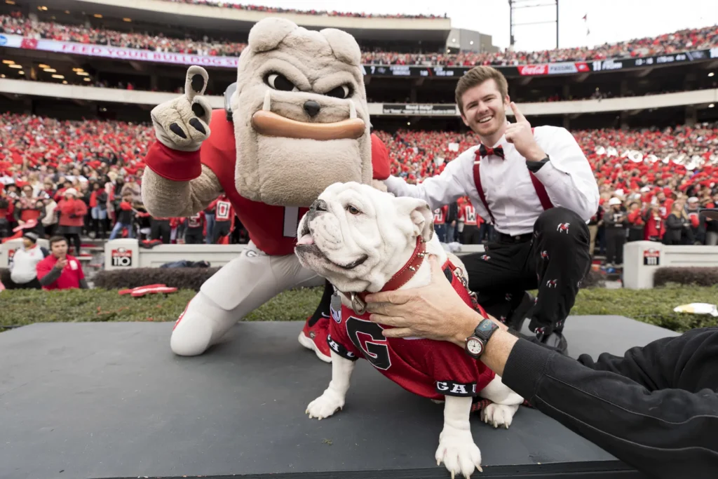 A young Chip Chambers dressed as Mic Man poses with a bulldog and a person dressed as a bulldog mascot.