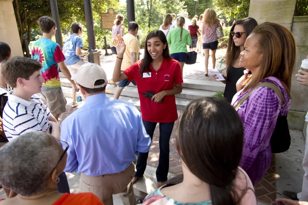 A young woman in a red UGA polo leads a tour at UGA.