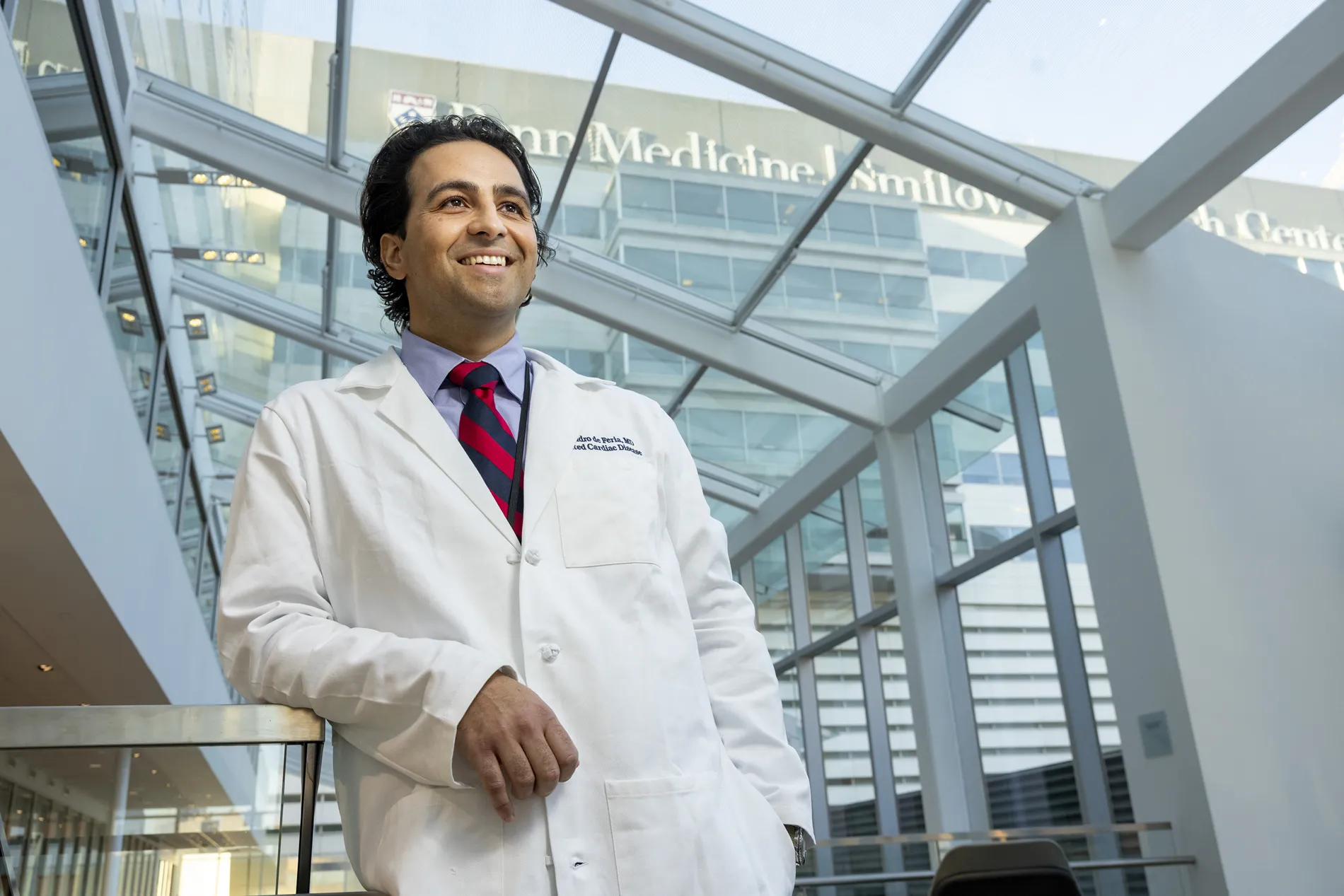 Alejandro de Feria wears a white medical jacket in the hallway of a medical center.