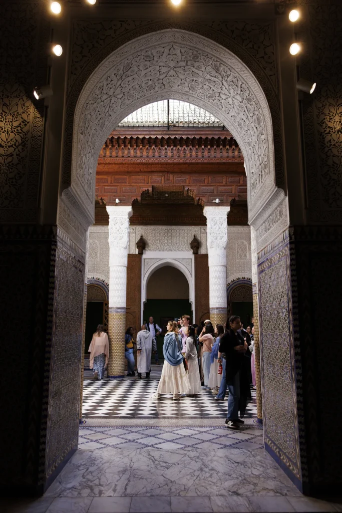 A closeup of a large arch in an outside wall. Several people can be seen through the arch.
