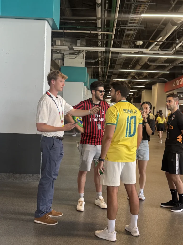 Several college students stand in a hallway talking to each other.