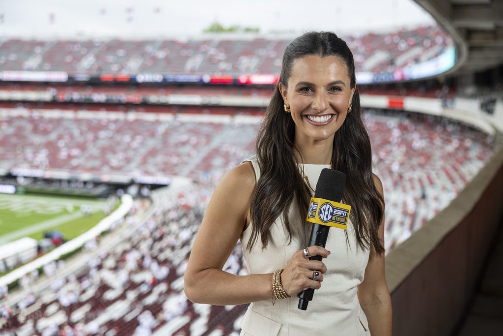 A closeup of a woman reporting for the SEC during a football game.