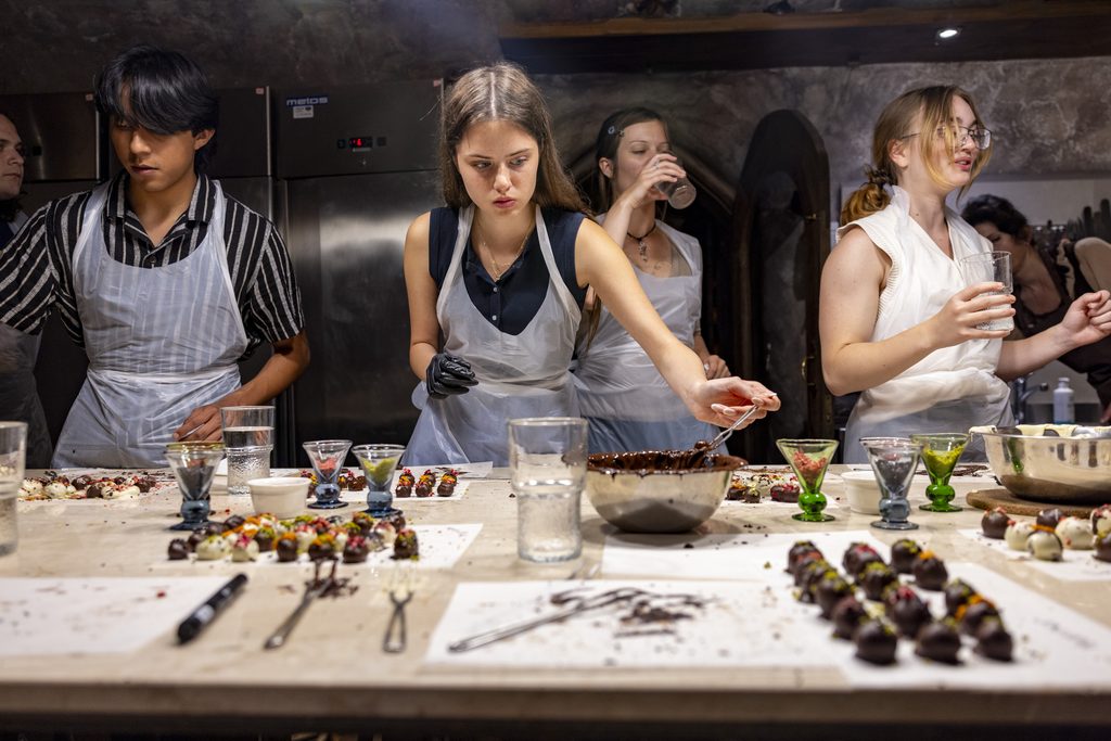 Four students standing at a table while shaping truffles.