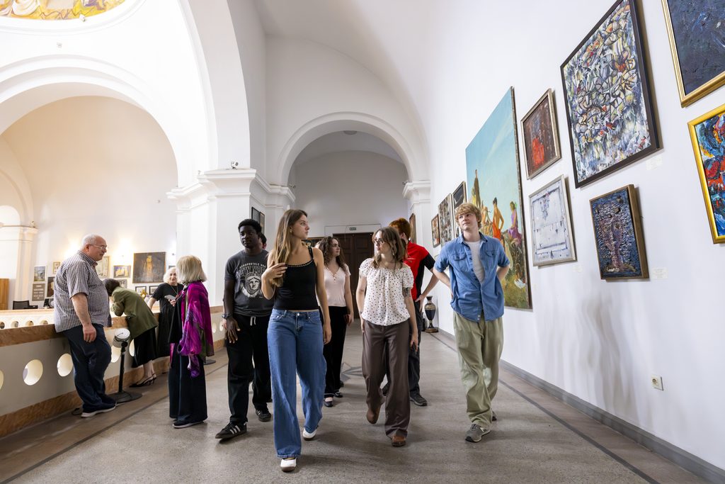 Students examining artwork and artifacts in a brightly lit museum gallery.