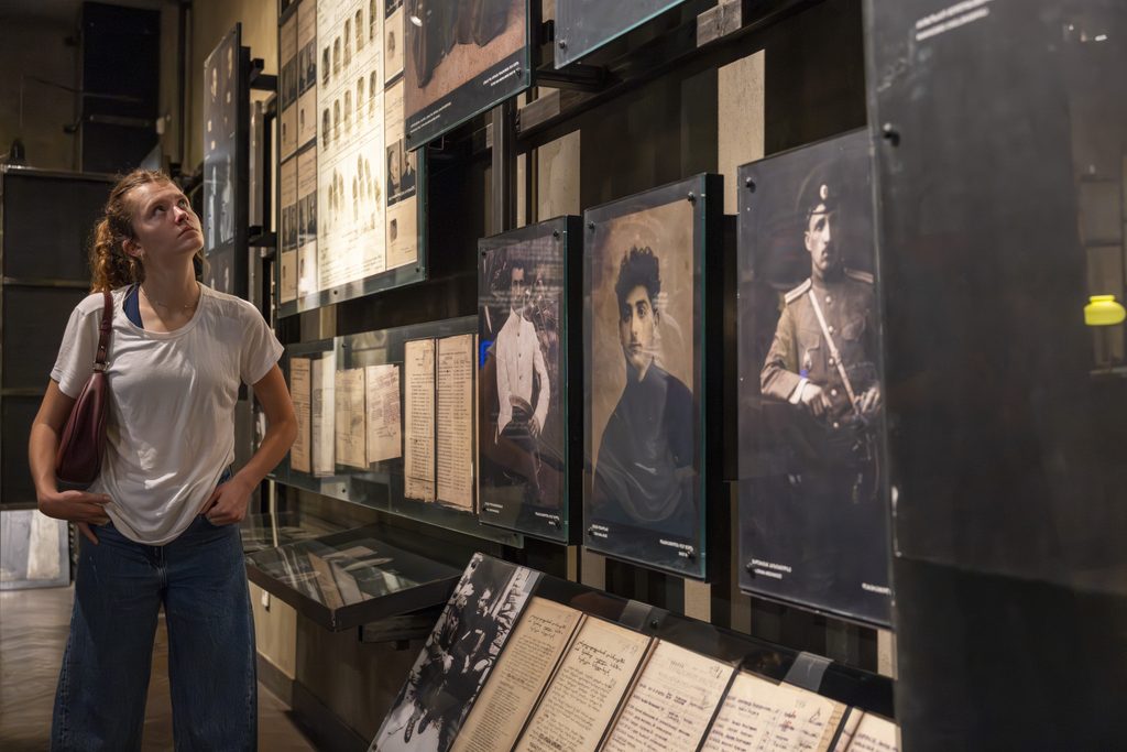 A female student looking closely at a museum wall display featuring black-and-white historical photographs.